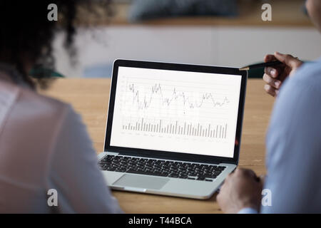 Rear view at african analysts analyze financial report on laptop Stock Photo