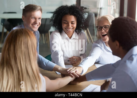 Happy multi ethnic employees stacking hands engaged in team building Stock Photo