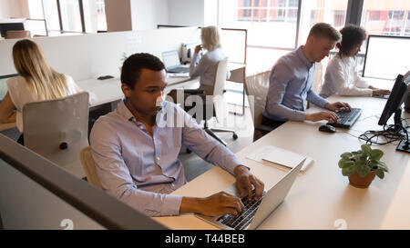 Multicultural staff business people sitting at desks working in office Stock Photo