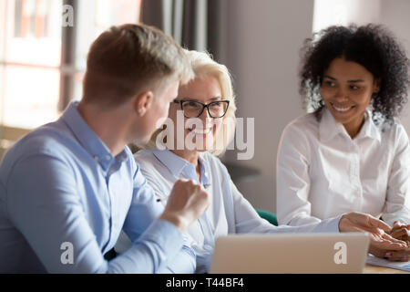 Smiling mature female mentor executive talking at diverse group meeting Stock Photo