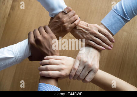 Diverse business people team grasping hands, close up top view Stock Photo