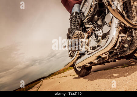 Biker girl riding on a motorcycle. Bottom view of the legs in leather boots. Stock Photo