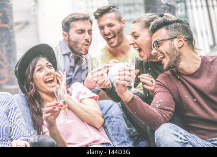 Group of happy friends making party drinking champagne while throwing confetti outdoor - Young people laughing and having fun celebrating holidays Stock Photo