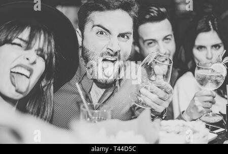 Friends having fun drinking cocktails and taking selfie in the bar - Young people taking photo in the club making silly faces Stock Photo