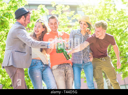 Group of friends enjoying beers outdoor - Happy young people having fun together toasting bottles of beer in the city - Youth friendship party concept Stock Photo