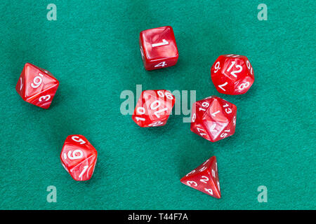 set of red polyhedral dices for Dungeons and Dragons board game playing on green baize table Stock Photo