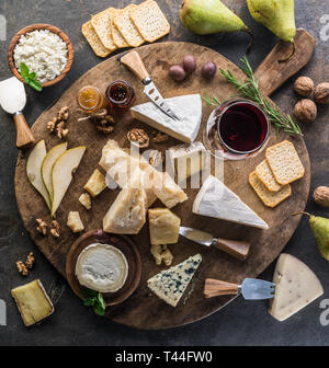CheCheese platter with different cheeses, fruits, nuts and wine on stone background. Top view. Tasty cheese starter. Stock Photo