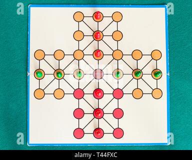 top view of cross solitaire board game on green baize table. The first mention of peg solitaire game can be identified in France in 1697 Stock Photo