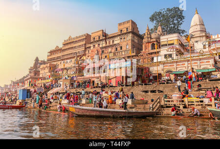 Varanasi Ganges river bank with historic city architecture at sunrise with wooden boat and tourists at Varanasi ghat Stock Photo