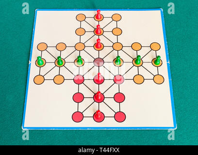 setup of cross solitaire board game on green baize table. The first mention of peg solitaire game can be identified in France in 1697 Stock Photo