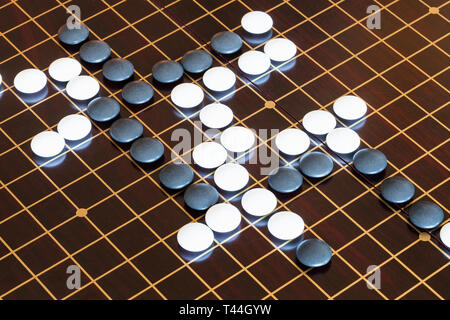 playing stones on wooden board in Go board game Stock Photo