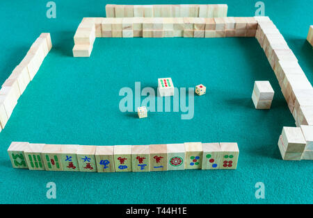 player's set at the beginning of mahjong game , tile-based chinese strategy board game on green baize table Stock Photo