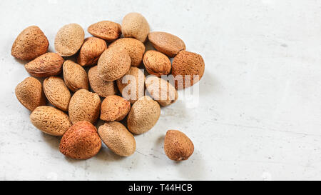 Whole almonds in shell, on white board. Stock Photo