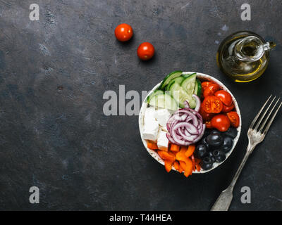 Greek Salad Bowl on dark black background, copy space. Above view of Bowl Greek Salad and ingredients. Trendy food. Idea, recept and concept of modern healthy food. Stock Photo