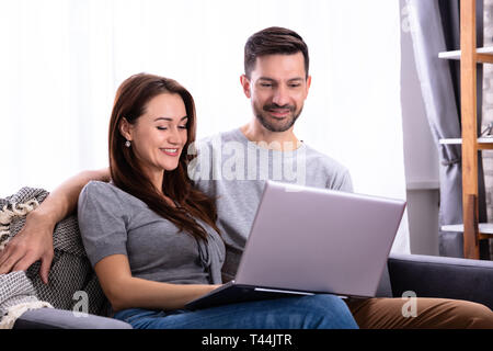 Smiling Young Couple Working Laptop At Home Stock Photo