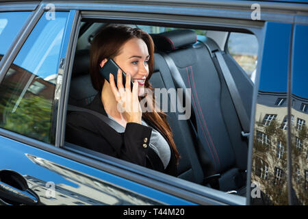 Happy Young Businesswoman Sitting Inside Car Talking On Smartphone Stock Photo