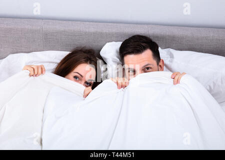 High Angle View Of An African Couple Trying To Hide In Blanket Stock Photo