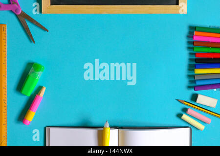 Education or back to school concept : top view or flat lay of chalks, pencil, magic colors, eraser, oil pastels, scissors, notebook with copy space Stock Photo