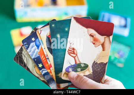 MOSCOW, RUSSIA - APRIL 3, 2019: player shows picture cards in Imaginarium game. Imaginarium is card game for stories and associations, russian variant Stock Photo