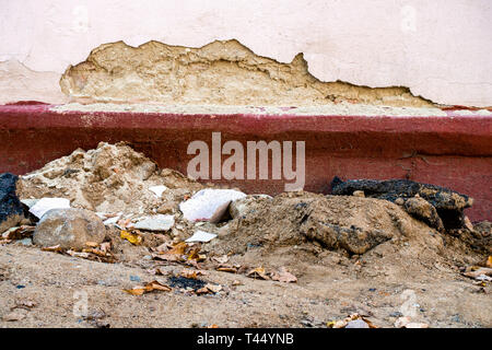 in the apartment house the wall is destroyed. from the building plaster fell off. There are rocks and sand lying on the ground Stock Photo