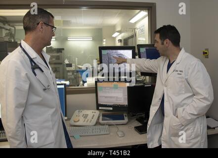 U.S. Air Force Lt. Col. (Dr.) Joseph Sky, (left) chief of cardiology and Lt. Col. (Dr.) Shea Pribyl, surgeon, both with the 60th Medical Group, David Grant USAF Medical Center, discuss the best approach to treat a blocked artery, Feb. 26, 2019, at Travis Air Force Base, California. With increased emphasis placed on non-invasive cardiology procedures and imaging techniques done on an outpatient basis, DGMC uses some of the latest technology in the evaluation and treatment of heart disease. Stock Photo