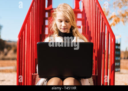 young girl schoolgirl doing lessons. teenager sits on the red stairs in the street Stock Photo