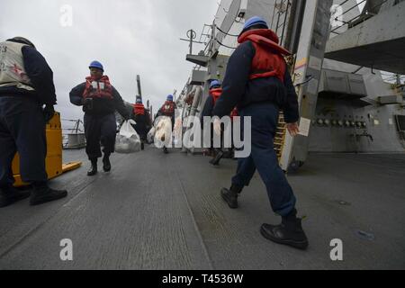 SOUTH CHINA SEA (Feb. 28, 2019) - Sailors aboard the Arleigh Burke-class guided-missile destroyer USS Stethem (DDG 63) take out trash during a replenishment-at-sea. Stethem is forward-deployed to the U.S. 7th Fleet area of operations supporting security and stability in the Indo-Pacific region. Stock Photo