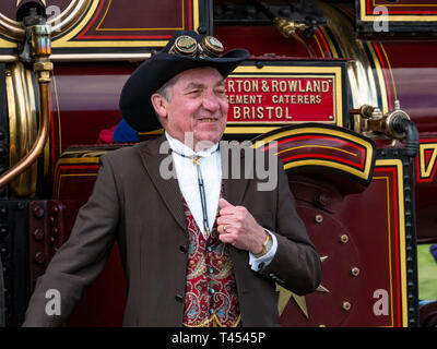 Beamish, Durham County, England, United Kingdom, 13 April 2019. Beamish Steam Day: A Steampunk enthusiast man wearing vintage style clothes and a steampunk hat poses in front of an Anderton & Rowland steam traction engine at Beamish Living Museum Stock Photo