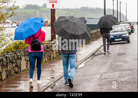 Bantry, West Cork, Ireland. 14th Apr, 2019. People walk in the rain in Bantry this afternoon.  County Cork is currently in the midst of a Status Yellow Rainfall and Wind Warning which lasts until 6pm Monday. Credit: Andy Gibson/Alamy Live News. Stock Photo