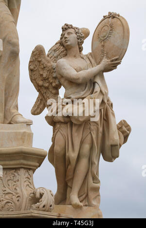 Baroque statue of an angel holding the plaque with the christogram of the Jesuits from the sculptural group of Saint Francis Borgia by Czech sculptor Ferdinand Maxmilián Brokoff on the Charles Bridge in Prague, Czech Republic. The current statue on the bridge is a copy dated from 2018-2019 after an original dated from 1710. Stock Photo