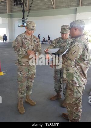 SAIPAN, Commonwealth of the Northern Mariana Islands – (From left) Army Sgt. Shane Castro, 368th Military Police Company, Army Staff Sgt. Charlie Garbertan, 368th Military Police Company, Army Sgt. Magic Cabrera, E Co., 100TH BN, 442nd INF , 9th Mission Support Command,  gather their score sheets during the CNMI Junior Reserve Officer Training Corps Drill Meet, Mar. 3, Kobler Gym, Koblerville, Saipan. The three Soldiers are among the twelve who volunteered to support the 2019 CNMI JROTC Drill Meet. Stock Photo