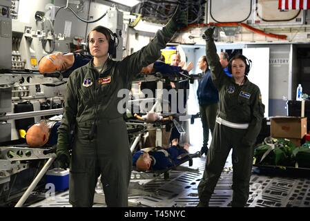 U.S. Air Force Tech Sgt. Katelyn Goorhouse, an aeromedical evacuation technician from the 109th Aeromedical Evacuation Squadron, Minnesota Air National Guard, and Tech Sgt. Joylynn Bishop, an aeromedical evacuation technician with the 156th Aeromedical Evacuation Squadron, North Carolina Air National Guard, signal for the on-loading of patients to a C-17 Globemaster III, during the PATRIOT South 19 exercise, March 5, 2019, on the flightline at the Savannah Air National Guard Base, Georgia. PATRIOT South 19, a domestic operations disaster-response training exercise conducted by National Guard u Stock Photo