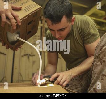 GULF OF OMAN (March 10, 2019) U.S. Marine Lance Cpl. Jared Gillan, a military police Marine with the 22nd Marine Expeditionary Unit, fills a Humvee battery  with battery fluid in the well deck of the Wasp-class amphibious assault ship USS Kearsarge (LHD-3). Marines and Sailors with the 22nd MEU and Kearsarge Amphibious Ready Group are deployed to the 5th Fleet area of operations in support of naval operations to ensure maritime stability and security in the Central Region, connecting the Mediterranean and the Pacific through the western Indian Ocean and three strategic choke points. Stock Photo