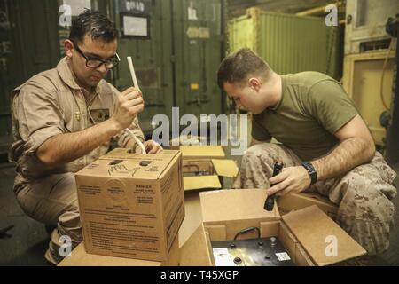 GULF OF OMAN (March 10, 2019) U.S. Marine Staff Sgt. Oswaldo Valenzuela, left, a maintenance chief and Lance Cpl. Colton Glasson, a motor transport mechanic, both from the 22nd Marine Expeditionary Unit, prepare to fill Humvee batteries with battery fluid in the well deck of the Wasp-class amphibious assault ship USS Kearsarge (LHD-3). Marines and Sailors with the 22nd MEU and Kearsarge Amphibious Ready Group are deployed to the 5th Fleet area of operations in support of naval operations to ensure maritime stability and security in the Central Region, connecting the Mediterranean and the Pacif Stock Photo