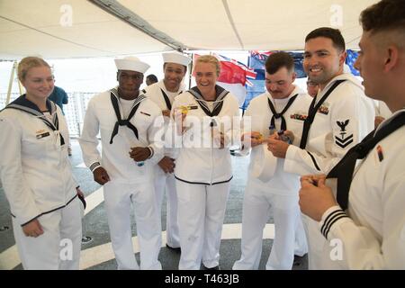 SUNDA STRAIT (March 1, 2019) Sailors assigned to the Avenger-class mine countermeasures ship USS Chief (MCM 14), accept Vegemite from Australian sailors after a memorial service aboard the Indonesian Navy (TNI-AL) ship Kri Usman Harun (359). The ceremony was held to honor the American and Australian crews of USS Houston (CA 30) and HMAS Perth (D 29) that lost their lives in battle against the Japanese Imperial Navy during World War II. Stock Photo