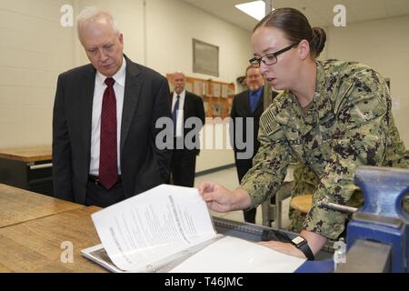 PENSACOLA, Fla. (March 13, 2019) Aviation Structural Mechanic 1st Class Megan Stricklin, right, an instructor at Naval Air Technical Training Center (NATTC), explains how naval aviation maintenance technicians are taught in the metal fabrications lab to Charles Drummond, deputy assistant secretary of defense for education and training in the Office of the Assistant Secretary of Defense for Readiness.  Drummond toured NATTC during a visit to Pensacola that also included Naval Education and Training Command, where he discussed topics such as credentialing; Ready, Relevant Learning; and informati Stock Photo