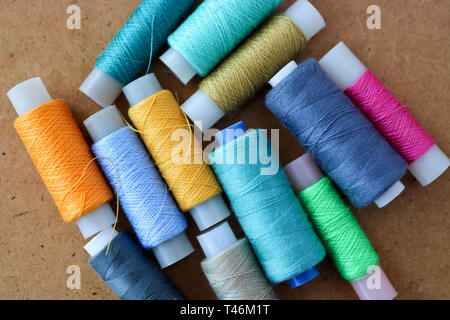 Multicolor sewing threads on a roll for sewing on a wooden background Stock Photo