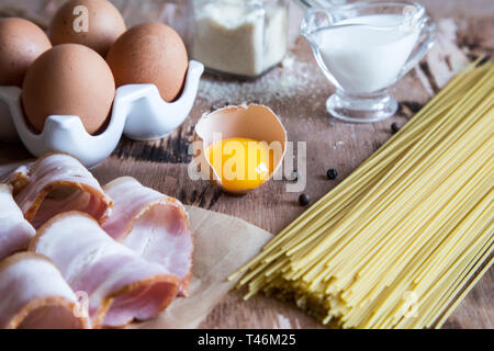 Ingredients for Pasta Carbonara with bacon, cheese, cream and yolk on wooden table. Preparing Spaghetti alla carbonara Stock Photo