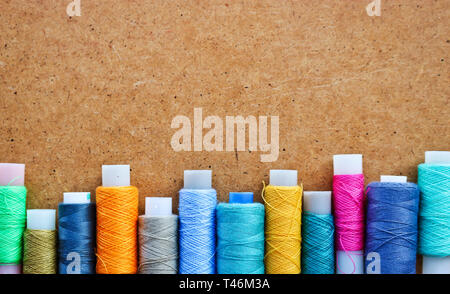 Multicolored threads on a roll for sewing on a blurred wooden background. With copy space Stock Photo
