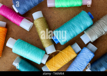 Multicolor sewing threads on a roll for sewing on a wooden background Stock Photo