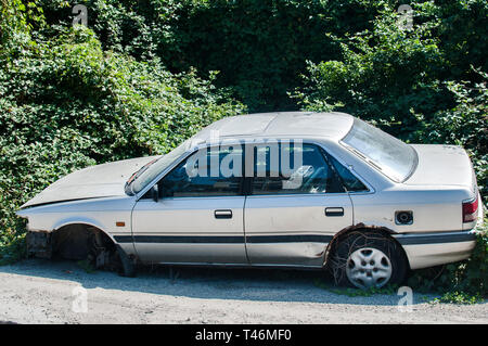 Old crushed cars bodies stored in auto wrecking junk yard for scrap and spare parts Stock Photo