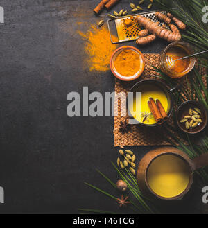 Top view of detox turmeric milk preparation and ingredients on dark background, top view. Copy space. Healthy hot beverages concept. Natural immune bo Stock Photo