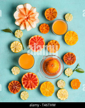 Various colorful citrus fruits half with juice in glasses on blue background, top view. Flat lay. Healthy lifestyle . Tropical summer citrus assortmen Stock Photo