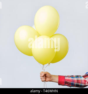 Yellow air flying balloons in man hands isolated on white background. Stock Photo