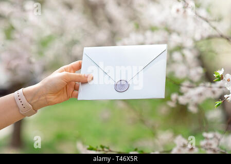 Wedding invitation cards, craft envelopes, pink and white flower and green leaves on white background Stock Photo