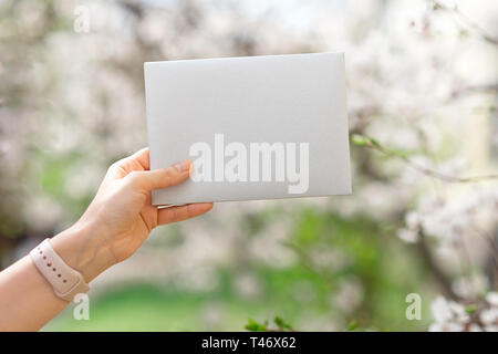 Wedding invitation cards, craft envelopes, pink and white flower and green leaves on white background Stock Photo