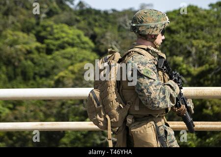 Cpl. Neil Plante, a rifleman and team leader with Charlie Company, Battalion Landing Team, 1st Battalion, 4th Marines, crosses a bridge during a live-fire range as part of the 31st Marine Expeditionary Unit's simulated Expeditionary Advanced Base Operations, Camp Schwab, Okinawa, Japan, March 13, 2019. Plante, a native of Shelbyville, Kentucky, graduated from Martha Layne Collins High School in May 2015 before enlisting in August the same year. Marines with the 31st MEU are conducting simulated EABO in a series of dynamic training events to refine their ability to plan, rehearse and complete a Stock Photo