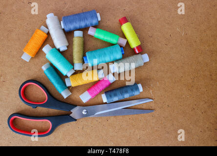Multicolor sewing threads on a roll for sewing and tailoring scissors on a wooden background. With copy space Stock Photo
