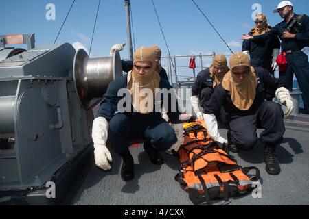 SOUTH CHINA SEA (March 15, 2019) Sailors prepare to lift a stretcher during a general quarters drill aboard the Avenger-class mine countermeasures ship USS Chief (MCM 14). Chief, part of Mine Countermeasure Squadron 7, is operating in the Indo-Pacific region to enhance interoperability with partners and serve as a ready-response platform for contingency operations. Stock Photo