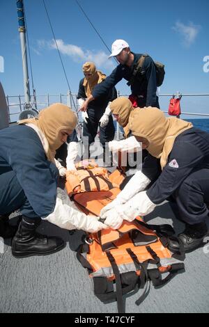 SOUTH CHINA SEA (March 15, 2019) Sailors secure a dummy to a stretcher during a general quarters drill aboard the Avenger-class mine countermeasures ship USS Chief (MCM 14). Chief, part of Mine Countermeasure Squadron 7, is operating in the Indo-Pacific region to enhance interoperability with partners and serve as a ready-response platform for contingency operations. Stock Photo